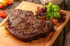 a steak on a cutting board next to some vegetables