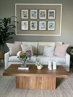 a living room with couches, coffee table and pictures on the wall above it