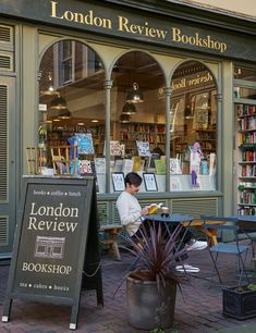 a man sitting at a table in front of a book store