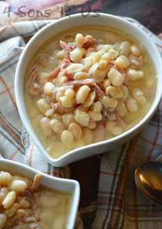 two bowls filled with beans and ham on top of a plaid cloth next to spoons