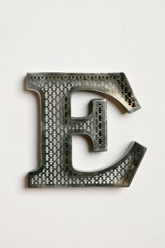 the letter e is made up of small silver dots on a white wall with a black border