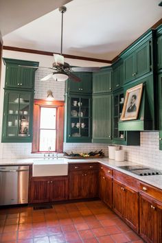 a kitchen with green cabinets and tile flooring is pictured in this image, there are pictures on the wall above the sink