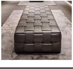 a long leather bench sitting on top of a cement floor