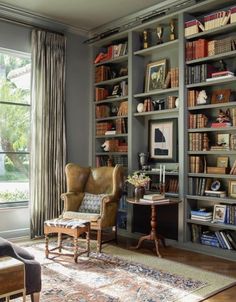 a living room filled with lots of furniture and bookshelves next to a window