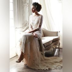 a woman is sitting on a chair wearing a dress with sheer sleeves and lace detailing