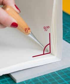 a woman is writing on a piece of paper with a pencil and ruler in her hand