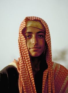 a young man wearing an orange and white head scarf