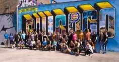 a group of people posing for a photo in front of a wall with the word chicago painted on it