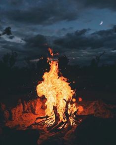 there is a fire burning in the middle of the night with dark clouds behind it