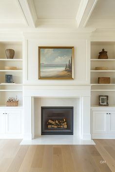 a fireplace in a living room with white bookcases and a painting on the wall