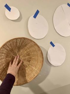 the person is working on some paper circles that are hanging on the wall with blue tape