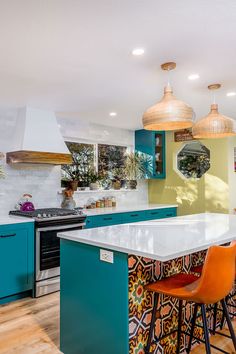 a kitchen with blue cabinets and an island in the middle, surrounded by orange chairs