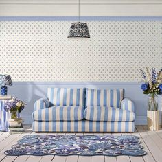 a blue and white striped couch in a room with polka dot wallpaper on the walls