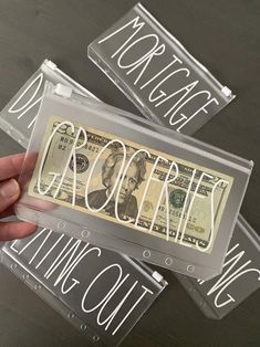 two clear acrylic business cards with words and money in the middle one being held by a hand