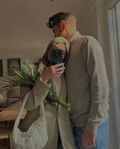 a man and woman taking a selfie in front of a mirror with flowers on it