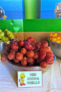 some grapes and oranges are in bowls on a table with a sign that says red koola shells