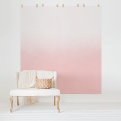 a white chair sitting in front of a wall with a pink ombreed background