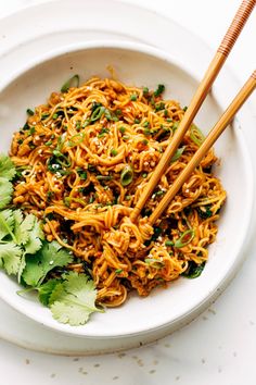 two chopsticks in a bowl of noodles with cilantro