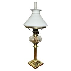 a white lamp with a gold base and a glass shade on it's top