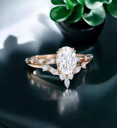 a diamond ring sitting on top of a black table next to a potted plant