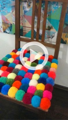 a wooden chair with multi colored pom - poms on it