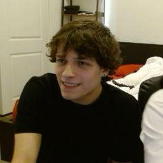 a young man sitting on top of a bed in front of a white closet door