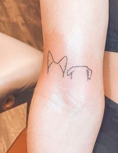 a woman's arm with a small dog tattoo on the left side of her leg