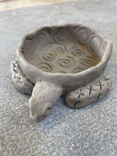 a ceramic turtle shaped bowl sitting on the ground