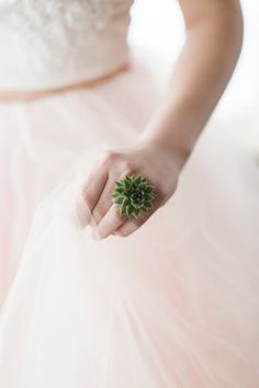 a woman in a pink dress holding a green flower