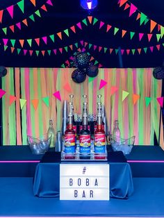 a table topped with bottles of soda and condiments in front of a colorful backdrop