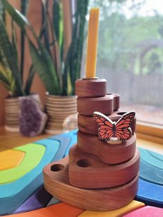 a wooden toy with a butterfly on it and a candle in the middle next to some plants