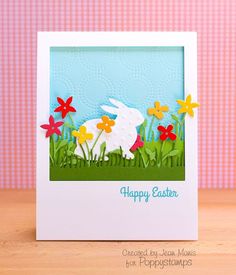 a card with an easter bunny in the grass and flowers on it, that says happy easter