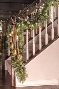 a christmas garland with bells and greenery on the banisters in front of a staircase