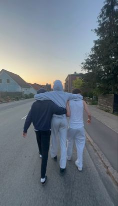 three people walking down the street with their arms around each other