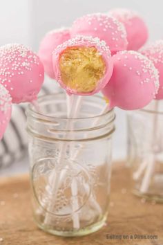 pink cake pops with white sprinkles in a mason jar on a table