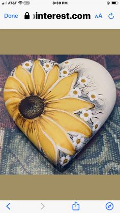 a painted heart shaped rock with yellow and white flowers