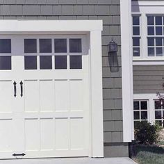 a white garage door in front of a gray house