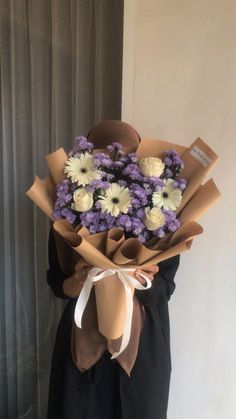 a person holding a bouquet of flowers in front of a window with curtains behind them