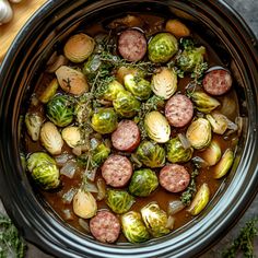 a crock pot filled with sausage and brussel sprouts