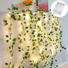 a white curtain with green leaves hanging from it's sides and lights on the side