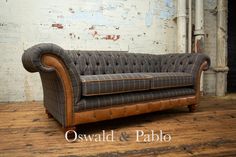 an old leather couch sitting on top of a wooden floor next to a white brick wall