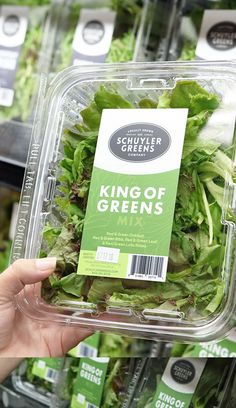 a person holding up a plastic container filled with lettuce