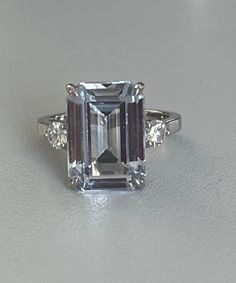 White gold (18k) ring adorned with an emerald-cut aquamarine of approximately 7.91 ct (13 x 9 mm) supported on each side by a round brilliant-cut diamond of approximately 0.17 ct each. Gross Weight: 5.95 g. Size: 51.5 Possibility of sizing, contact us. Further information : We issue an invoice as well as a certificate of authenticity established by our qualified gemologist (LFG Paris). Our photos are not reworked and are taken in a natural light environment. We can send you a short video upon si Formal Aquamarine Diamond Ring With Brilliant Cut, Aquamarine Brilliant Cut Diamond Ring For Formal Occasions, Formal Aquamarine Ring With Diamond Accents, Elegant Gia Certified Blue Topaz Diamond Ring, Formal Aquamarine Diamond Ring, Formal Aquamarine Diamond Ring With Prong Setting, Formal Aquamarine Diamond Ring With Gemstone, Luxury Gia-certified Emerald Cut Topaz Ring, Elegant Asscher Cut Topaz Ring For Anniversary