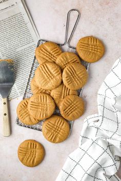 peanut butter cookies sitting on top of a cooling rack next to an open book and spatula