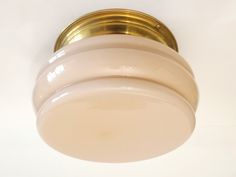 a close up of a light fixture on a white wall with a gold rim and round glass shade