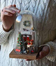 a woman holding a glass dome with christmas decorations inside