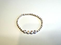 White and gold stretch bracelet that stash "hope" in alphabet letters Gold Stretch Bracelet, Hope Bracelet, L Alphabet, Alphabet Letters, Stretch Bracelet, Stretch Bracelets, Lettering Alphabet, Portland, Wedding Gifts