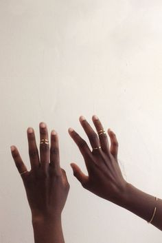 two hands reaching up towards each other with gold rings on their fingers and one hand in the air