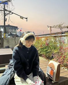 a woman sitting on top of a bench next to a toaster