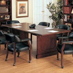 a conference table with chairs around it in front of a bookcase filled with books